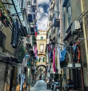 a narrow alley with clothes hanging from buildings at La Stanza a parte in Naples