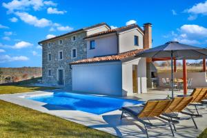 eine Villa mit einem Pool, Stühlen und einem Sonnenschirm in der Unterkunft Villa Marušići 2140 in Marušići