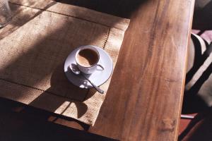 a cup of coffee on a plate on a wooden table at Amery House in Sliema