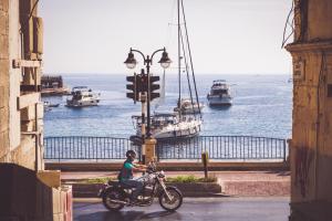 a person riding a motorcycle on a street with boats at Amery House in Sliema