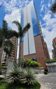 a tall building with palm trees in front of it at Alphaville Stay Residences in Barueri