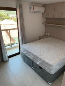 a small bedroom with a bed and a balcony at Anjos Beach in Arraial do Cabo