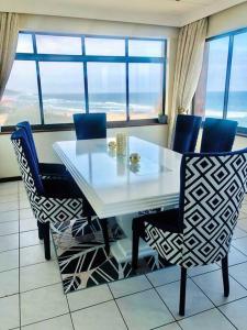 uma sala de jantar com uma mesa branca e cadeiras azuis em Penthouse 42 at Ezulweni em Amanzimtoti