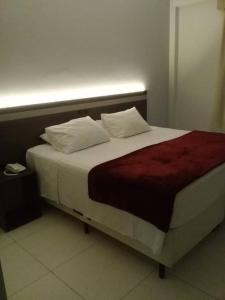 a bed with two pillows on it in a room at Hotel Vilhar in Ivaiporã