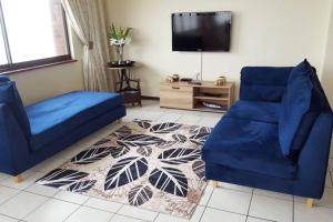 a living room with two blue chairs and a tv at Penthouse 42 at Ezulweni in Amanzimtoti