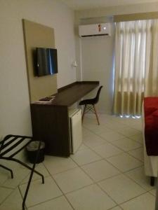 a kitchen with a counter and a table and a chair at Hotel Vilhar in Ivaiporã