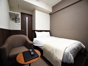 een slaapkamer met een bed en een stoel met afstandsbediening bij Land-Residential Hotel Fukuoka - Vacation STAY 81812v in Fukuoka