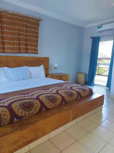 a bedroom with a large bed with a wooden headboard at Bamboo Garden Hotel in Serekunda