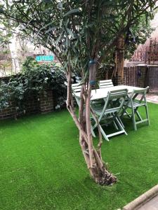 a table and bench next to a tree with green grass at Lovely 2 Bedroom Apartment Near South Bank in London