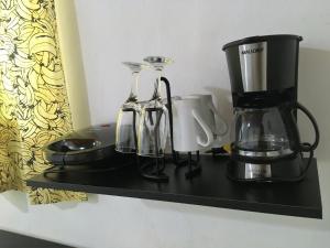 a black shelf with a coffee maker and cups on it at Jataí Guest House in Ubatuba