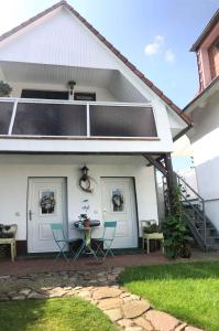 a white house with chairs and a table on a patio at Holiday home Groß Kordshagen/Ostsee 2774 in Flemendorf