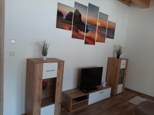 a living room with a tv and some paintings on the wall at Ferienwohnung Leni in Altaussee