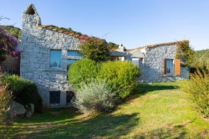 una vieja casa de piedra con flores en la fachada en Case Li Conchi G, en Castiadas