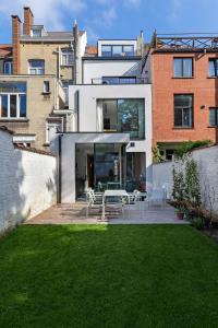 ein Haus mit einer Terrasse und einem Garten mit Gras in der Unterkunft Suite lumineuse à Saint-Gilles in Brüssel