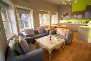 a living room with couches and a table and a kitchen at Cornerhouse Apartments Llandudno in Llandudno