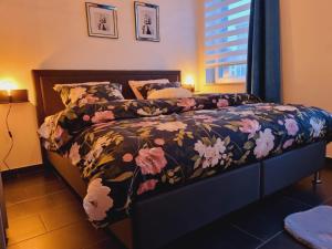 um quarto com uma cama com um edredão floral em La suite de lati em Liège