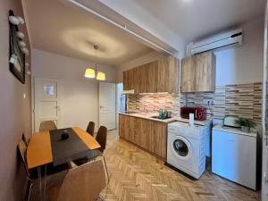 Bartók Apartment في سيجد: مطبخ مع غسالة ومجفف وطاولة