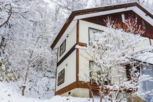 ein schneebedecktes Haus mit Bäumen in der Unterkunft La Colina Retreat - Vacation STAY 10109v in Madarao Kogen