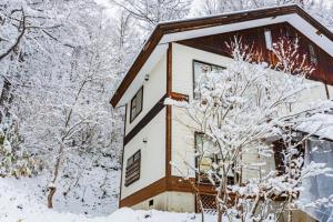 a house covered in snow with trees at La Colina Retreat - Vacation STAY 10109v in Madarao Kogen