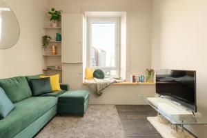 - un salon avec un canapé vert et une fenêtre dans l'établissement Spacious 2BR Leith Apartment, à Édimbourg