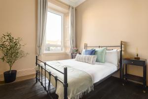 - une chambre avec un lit doté de draps blancs et une fenêtre dans l'établissement Spacious 2BR Leith Apartment, à Édimbourg