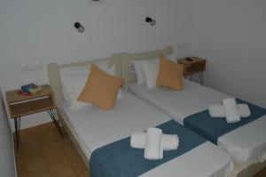two twin beds in a room with a side table at Pansion Katerina in Skiathos +18 photos