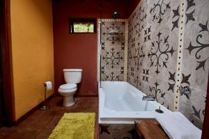 a bathroom with a white tub and a toilet at The Secret Garden Cotopaxi in Hacienda Porvenir