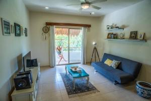 a living room with a blue couch and a tv at Aldea Zama Penthouse with Private Rooftop in Tulum