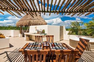 a patio with a table and chairs and an umbrella at Aldea Zama Penthouse with Private Rooftop in Tulum