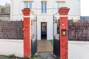 a white house with a black door and a fence at Jolie maison proche centre-ville et plages in Granville