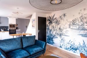 a living room with a blue couch and a painting on the wall at Jolie maison proche centre-ville et plages in Granville