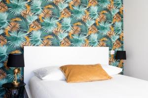 a bedroom with a white bed with a tropical wallpaper at Jolie maison proche centre-ville et plages in Granville
