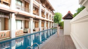 Eine Frau geht an einem Pool in einem Hotel vorbei in der Unterkunft T Heritage Hotel in Chiang Mai