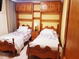 two beds in a room with wooden cabinets at PRECIOSO y AMPLIO apartamento a 2 minutos de la Playa in Arinaga