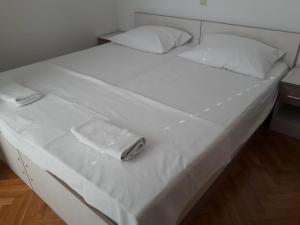 a large white bed with a white towel on it at Biserka in Novalja