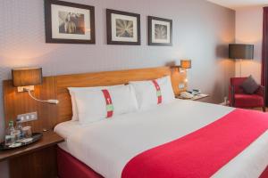 um quarto de hotel com uma cama grande e uma cadeira vermelha em Holiday Inn Norwich City, an IHG Hotel em Norwich