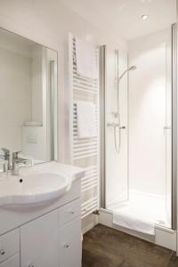 a white bathroom with a sink and a shower at Landhotel Hofgut Battenberg in Battenberg