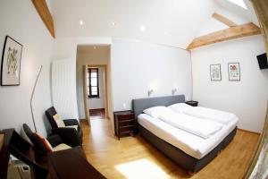 a bedroom with a large bed and a chair at Landhotel Hofgut Battenberg in Battenberg