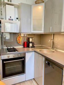 eine kleine Küche mit weißen Schränken und einer Spüle in der Unterkunft Cosy Central Riga Apartment in Riga + 15 Fotos