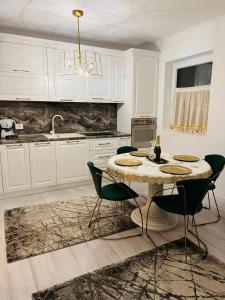 uma cozinha com uma mesa com cadeiras e um lavatório em Apartament Larysse em Oradea