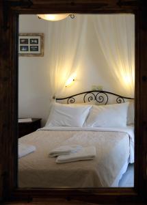 ein Spiegel, der ein Bett mit weißer Bettwäsche und Kissen reflektiert in der Unterkunft Pension Ilias - Chora Amorgos in Amorgós