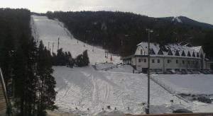 una colina cubierta de nieve con un edificio y una pista de esquí en APARTMA My HILL 5, en Maribor