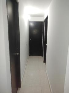 a hallway with a black door and a tile floor at Arriendo hermoso y amplio apartamento amoblado y con piscina, frente a la estación Niquia y al centro comercial puerta del norte. in Bello