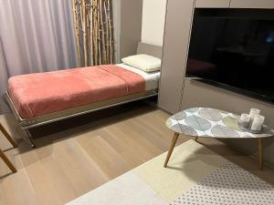 Zimmer mit einem Bett, einem Tisch und einem TV in der Unterkunft Pink Peony in Druskininkai
