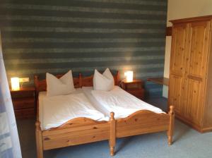 a bedroom with a wooden bed with white sheets and pillows at Gasthof Oberer Wirt in Kipfenberg