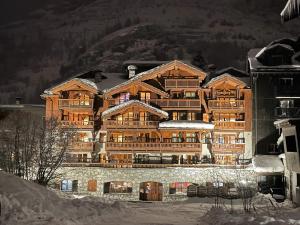 un grand bâtiment en bois avec de la neige au sol dans l'établissement Résidence Le Lys Martagon, à Val dʼIsère