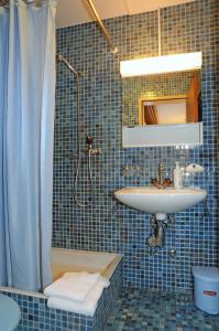 a blue tiled bathroom with a sink and a shower at Alpenhaus Bettmeralp in Bettmeralp