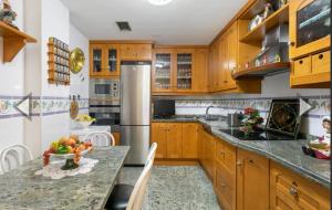 een keuken met houten kasten en een tafel met een fruitschaal bij Casa Luisa in Granada +2 foto's