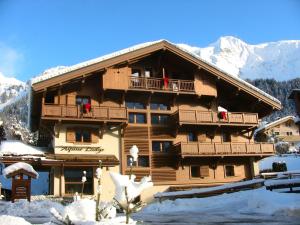 un grand bâtiment en bois avec de la neige au sol dans l'établissement Alpine Lodge 1, aux Contamines-Montjoie