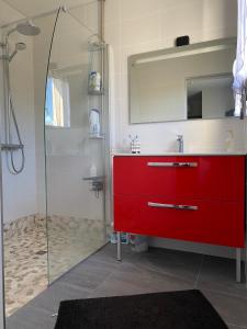 La salle de bains est pourvue d'un lavabo rouge et d'une douche. dans l'établissement Maison de Campagne, à Brignac-la-Plaine